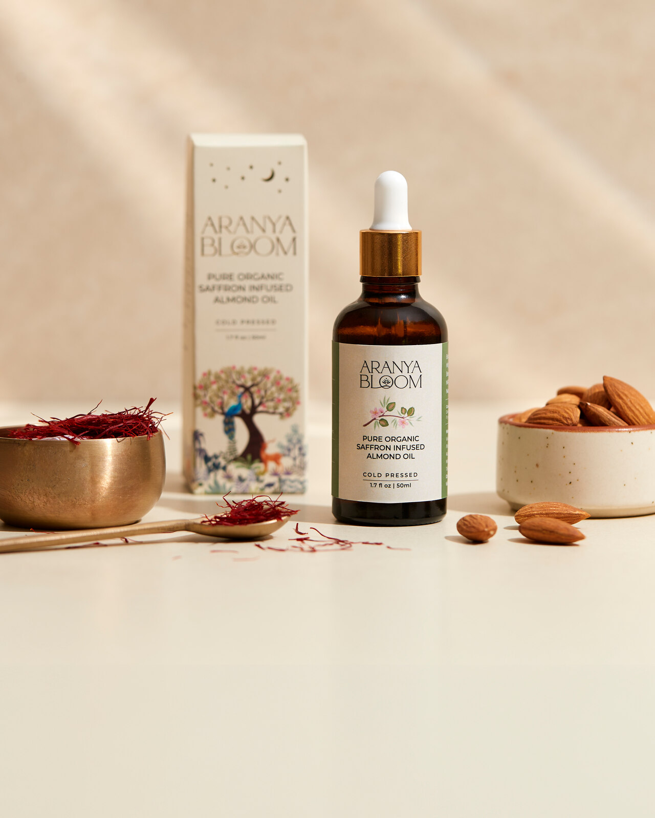 Aranya Bloom saffron almond oil bottle and carton on a warm neutral surface.
